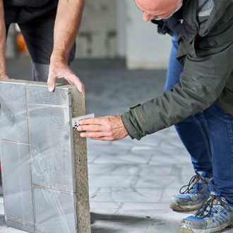 Handwerker misst die Stärke einer herausgetrennten Bodenprobe aus einem Rüttelbelag
